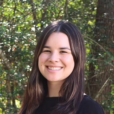 Chief Marketing Officer Ceci Falkenstein Smiling Outdoors In Front Of Greenery